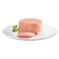 Fetta di paté di carne rosa su piatto bianco, decorata con foglia di prezzemolo fresco.