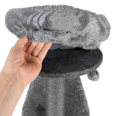 Hand showing removable grey plush cover of a scratching post element with sisal post and padded lying surface.