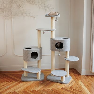 Kratzbaum mit mehreren Ebenen, zwei Höhlen und Spielbällen. Beige Sisalstämme und graue Plattformen. Katze oben auf der Liegefläche, zweite Katze in einer Höhle sichtbar.