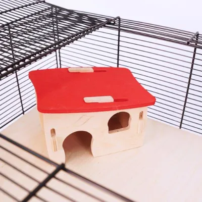 Houten huisje met rood dak in een metalen kooi, geschikt als schuilplaats voor kleine knaagdieren. Huisje heeft twee ingangen en een raamopening.