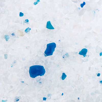 Witte en blauwe korrels kattenbakvulling, grove structuur duidelijk zichtbaar. Geen merknaam of extra informatie op de afbeelding.