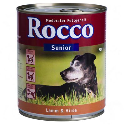 Blik Rocco Senior hondenvoer, 800 g, met zichtbare tekst: Moderater Fettgehalt, Lamm & Hirse. Duitse tekst: Ideales C/P, Leicht verdaulich, Kraft & Energie. Afbeelding van oudere hond.