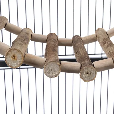 Pont suspendu en bois composé de rondins, installé dans une cage à barreaux métalliques. Bois brut visible, sans marque ni texte apparent.