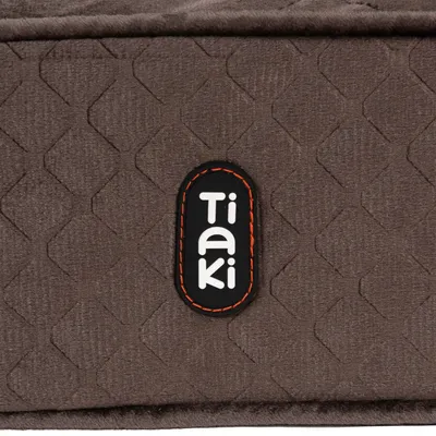 Logo de Tiaki sobre tela marrón con diseño geométrico.