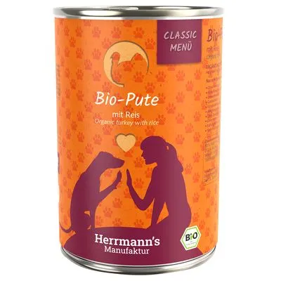 Blik met opdruk: Bio-Pute mit Reis, Classic Menü, Herrmann's Manufaktur, BIO-keurmerk. Illustratie van hond en persoon. Tekst deels in het Duits en Engels.