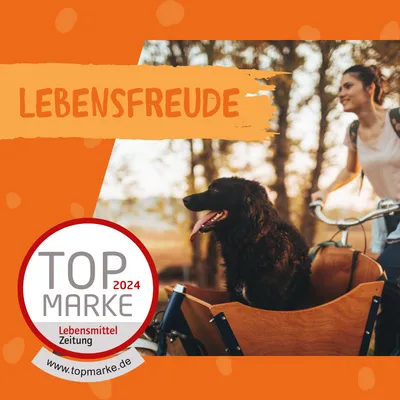 Texte allemand « LEBENSFREUDE ». Badge : TOP MARKE 2024 Lebensmittel Zeitung www.topmarke.de. Chien noir assis dans une caisse de vélo à côté d’une personne. Texte allemand « LEBENSFREUDE ». Badge : TOP MARKE 2024 Lebensmittel Zeitung www.topmarke.de. Chien noir assis dans une caisse de vélo à côté d’une personne.