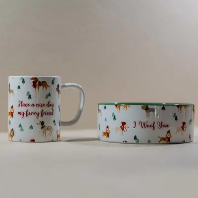 Mug avec texte anglais « Have a nice day my furry friend » et gamelle avec texte « I Woof You », motifs chiens et sapins visibles sur les deux objets.