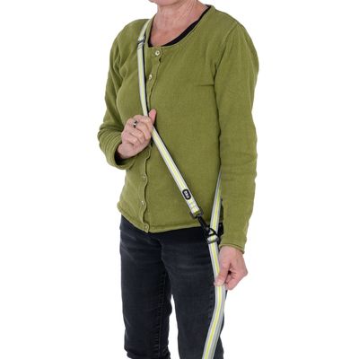 Osoba demonstruje użycie odblaskowej smyczy dla psa z paskiem na ramię. Smycz w kolorze żółtym i szarym, regulowana z karabińczykiem.