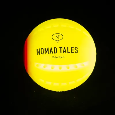 Palla gialla con la scritta 'Nomad Tales München' e logo NT.