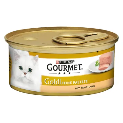 Purina Gourmet Gold fijne paté met kalkoen, kattenvoer in een goudkleurig blik met afbeelding van een witte kat en kalkoenpaté op een bord.