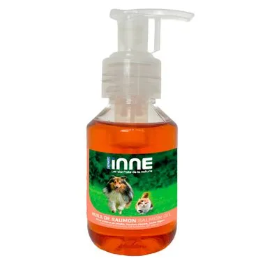 Fles met pompje, etiket: INNE, huile de saumon salmon oil. Afbeelding van hond en kat op groen gras. Tekst deels in Frans en Engels zichtbaar.