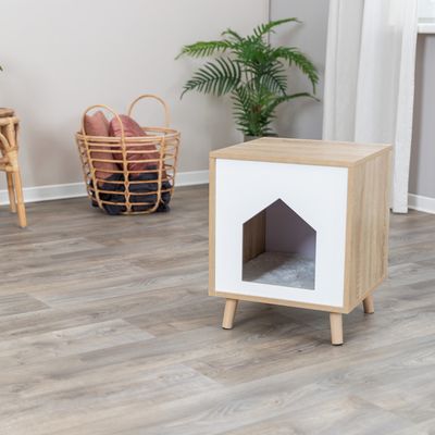 Husdjursmöbel i trä med vit front och husformad ingång, vadderad insida. Modern design med fyra ben, lämplig för inomhusbruk.