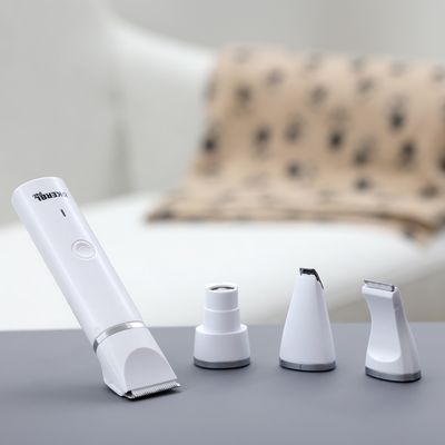 White pet hair trimmer by Trixie with four interchangeable attachments for different cutting styles, presented on a grey surface.