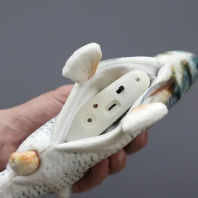 Plüschspielzeug in Fischform mit Reissverschluss, zeigt ein herausnehmbares elektrisches Modul mit USB-Anschluss und Schalter.