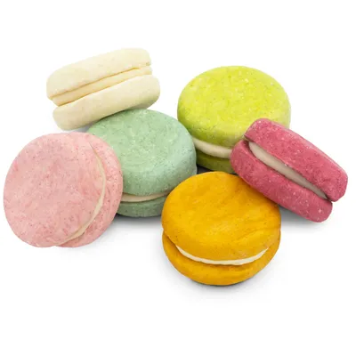 Assortiment de biscuits ronds pour animaux, cinq couleurs différentes (rose, jaune, vert, blanc, rouge), garnis d'une crème blanche au centre, posés sur fond blanc.