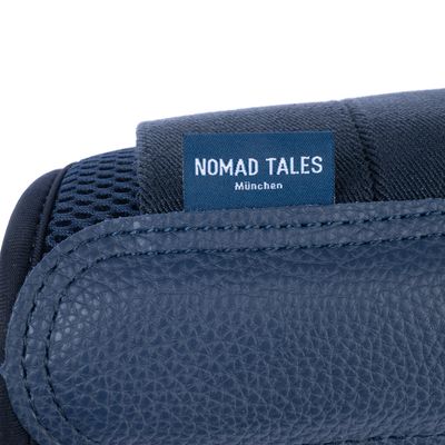 Nomad Tales München. Этикетка на темно-синем материале с кожаной и сетчатой текстурой.