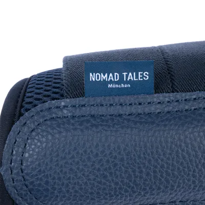 Nomad Tales München. Label op donkerblauw materiaal met leer- en netstructuur.
