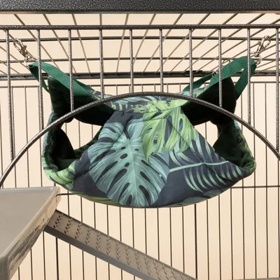 Hangmat met groen bladmotief, bevestigd aan metalen kooi met karabijnhaken.