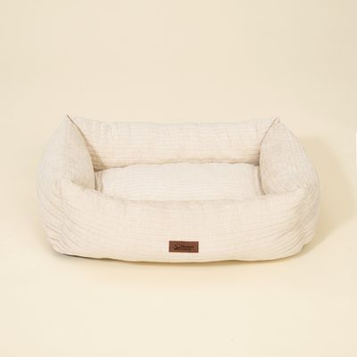 Rechteckiges, hellbeiges Bett mit Stoffstruktur und braunem Label mit Aufschrift 'Modern Living' auf der Vorderseite.