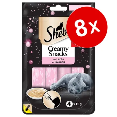Sheba Creamy Snacks au saumon, lot de 8 paquets. Visuel d’un chat gris, 4 sticks de 12 g chacun, indication pour donner à la main. Texte visible en français et allemand.