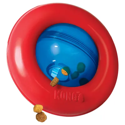 KONG leksak i röd och blå plast med synliga foderbitar som faller ut genom öppning. KONG-logotyp synlig på den röda delen.