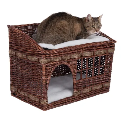 Kattenmand van bruin vlechtwerk met twee niveaus, boven een gevoerd ligvlak en onder een beschutte slaapruimte. Kat zit op het bovenste vlak.