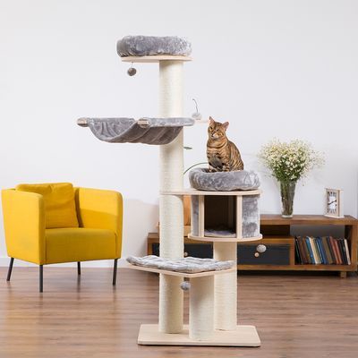 Krabpaal met meerdere niveaus, hangmat en grot van licht hout en beige stof. Bengal kat zit op een gevoerd platform. Woonkamerinrichting op de achtergrond.