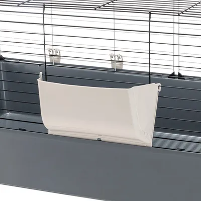 Jaula para pequeños animales con comedero blanco de plástico, fijado a rejilla metálica. Diseño en gris y blanco.