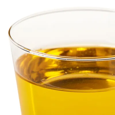 Verre transparent rempli d’un liquide jaune doré. Aucun texte ou marque visible sur le verre ou le liquide.