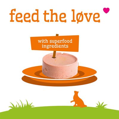 Text: feed the love. Z superfood-składnikami. Na zdjęciu widoczny jest okrągły kawałek karmy na talerzu.