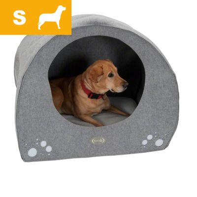 Hund i grå hundehule med pude, mærket 'S' og hvid silhuet af hund øverst til venstre. Synlig rød halsbånd på hunden. Materiale ligner stof.