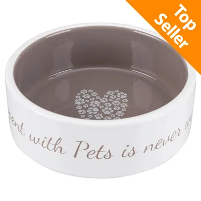 Ciotola in ceramica con interno marrone, decorata con cuore di impronte e scritta visibile: 'spent with Pets is never'. Etichetta arancione in alto a destra: Top Seller. Ciotola in ceramica con interno marrone, decorata con cuore di impronte e scritta visibile: 'spent with Pets is never'. Etichetta arancione in alto a destra: Top Seller.