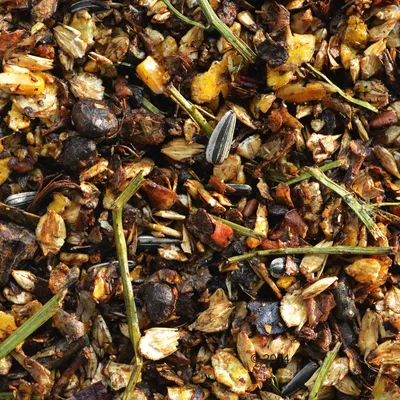 Close-up van gemengd vogelvoer met granen, zaden, gedroogd fruit en gras.