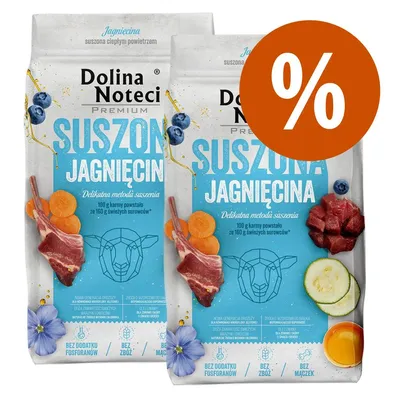 Due confezioni di Dolina Noteci Premium Suszona Jagnięcina con immagini di carne, carote, mirtilli e zucchine. Simbolo percentuale arancione in alto a destra.