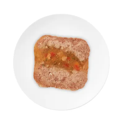 Close-up of a piece of wet food with meat and vegetables on a white plate.