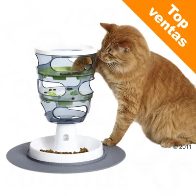 Gato junto a un comedero interactivo de plástico transparente y blanco con pienso en varios niveles. Esquina superior derecha: texto 'Top ventas' en fondo naranja. Gato junto a un comedero interactivo de plástico transparente y blanco con pienso en varios niveles. Esquina superior derecha: texto 'Top ventas' en fondo naranja.
