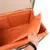 Innenansicht einer orangefarbenen, gepolsterten Box mit abnehmbarem Bezug. Hand hebt den Bezug an, um die Polsterung zu zeigen.