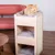 Tiragraffi in legno chiaro con tre livelli imbottiti e superficie laterale in corda, gatto arancione sdraiato sul piano superiore.