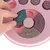 Pink interactive toy with movable parts in bone shape, hand demonstrates use by sliding a green element.