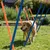 Chien beige passant entre des piquets d’agility orange et bleus installés sur une pelouse, démonstration d’un parcours d’agilité pour chiens en extérieur.