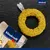 Vitakraft gul ring med frön och plasthållare, förpackningen visar Vitakraft-logotypen och texten 'Inget tillsatt socker'. Vitakraft gul ring med frön och plasthållare, förpackningen visar Vitakraft-logotypen och texten 'Inget tillsatt socker'.