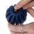 Main insérant une friandise dans un jouet bleu en caoutchouc pour animaux, forme ronde avec rainures et ouverture centrale visible.