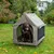 Hond in een draagbare, grijze outdoor-hondentent met gaasramen en stabiele constructie, opgezet in de tuin.