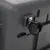 Roue noire en plastique fixée sur un angle d’une caisse ou boîte grise, fixation métallique visible. Aucun texte ou marque apparente.