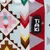 Logo Tiaki na látce s geometrickým vzorem v červené, hnědé, růžové a žluté barvě.