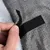 Nahaufnahme eines grauen Stoffmaterials mit Klettverschluss, der von einer Hand geöffnet wird.