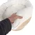 Hand hebt weiches, weisses, strukturiertes Polster von einer Holzplattform. Detailaufnahme der Materialbeschaffenheit.