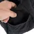 Close-up of a black bag with quilted seams, showing a hand opening a small outer pocket with a hook-and-loop fastener.