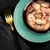 Bowl containing wet food with visible chunks of meat and seafood in gravy, shown on a plate with a fork beside it.