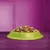 Bowl filled with assorted dry pet food pieces in various shapes and colours, displayed on a purple surface with a plain background.